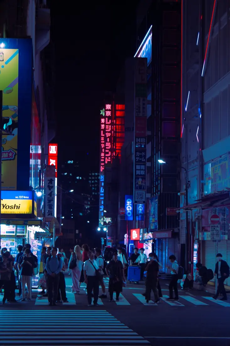 A crowded Tokyo street lit by deep blue and red neon