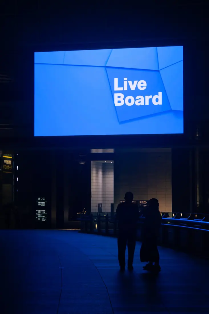 Two figures silhouetted beneath a glowing blue billboard