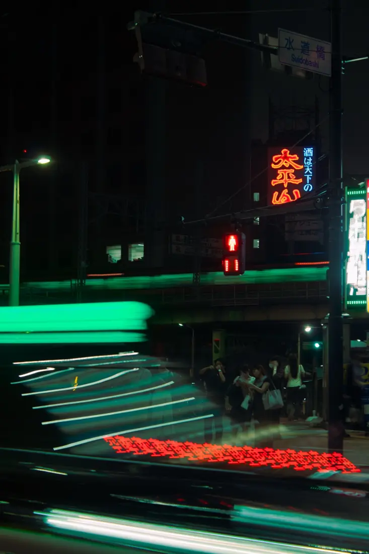 A taxi streaking through a Tokyo intersection in green and red light