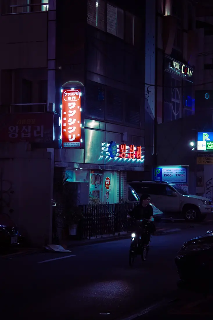 A cyclist moving through a violet-lit street at night